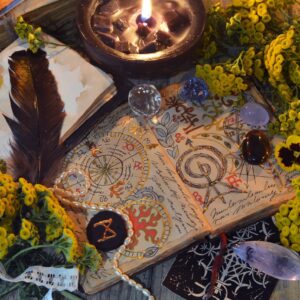Mystic still life with decorated magic book of spells, tarot card, tansy flowers, crystals, black candles and witchy ritual objects on old table. Occult, esoteric and wicca concept