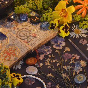 Mystic still life with open magic book of spells, flowers, crystals, black candles and witchy ritual objects on old table. Occult, esoteric, gothic and wicca concept