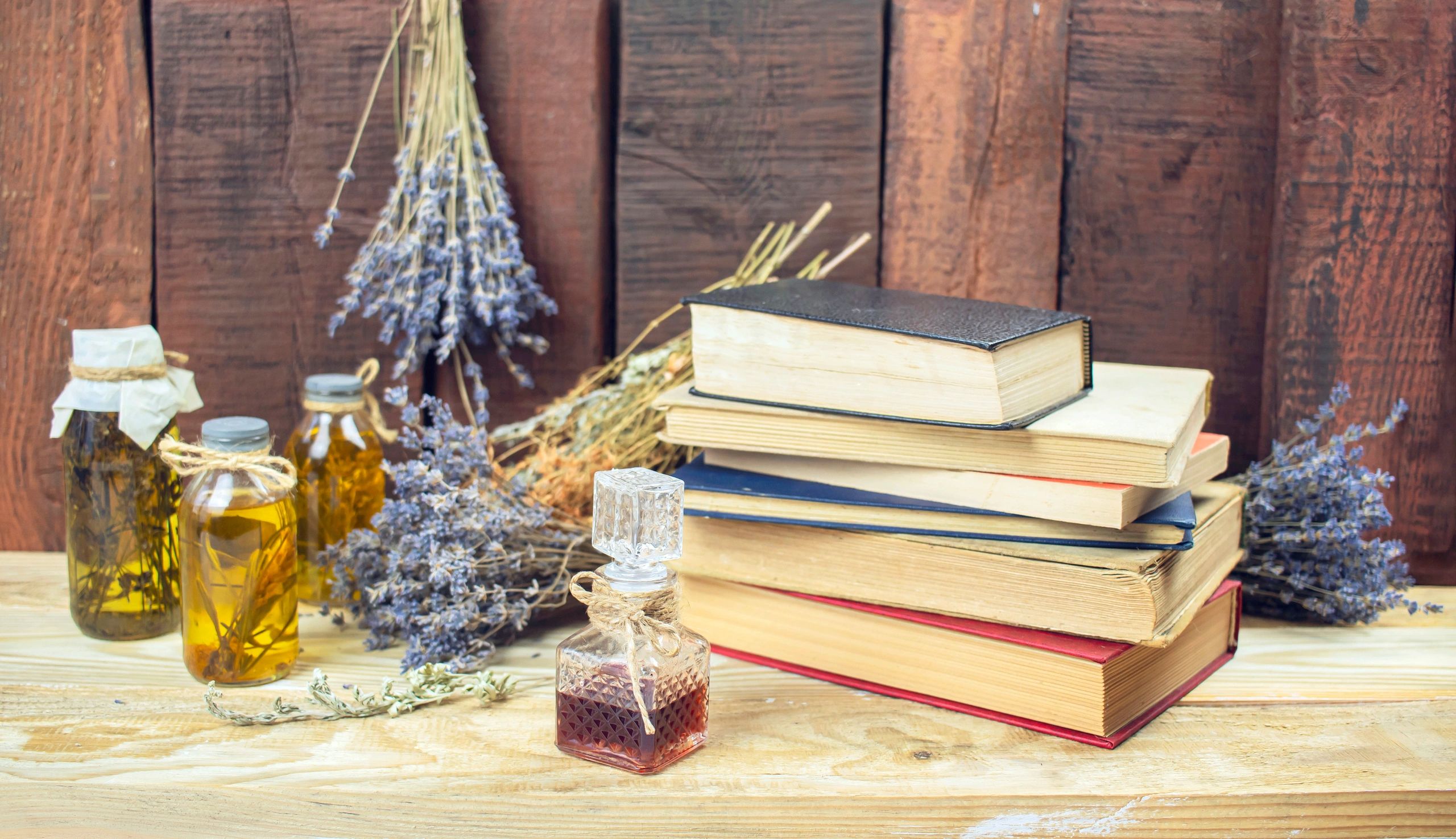 Ancient books, herbs, and candles arranged on a wooden surface