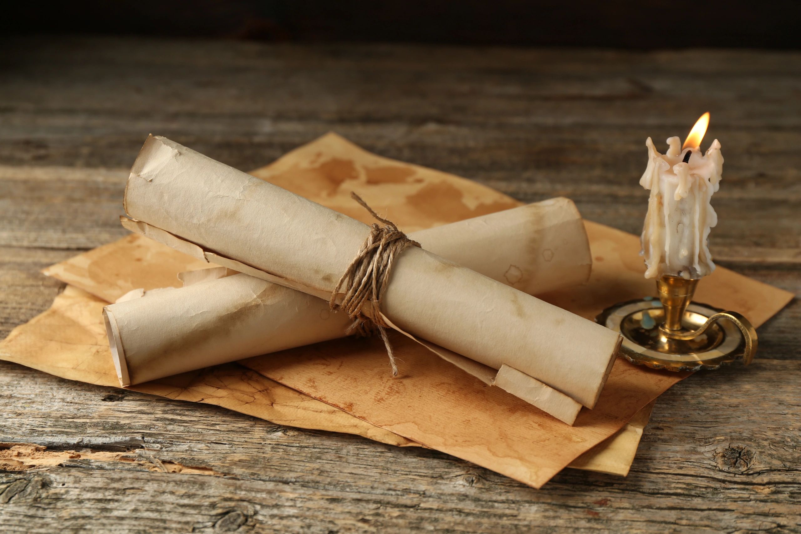 Old manuscript scrolls and candle on a wooden table