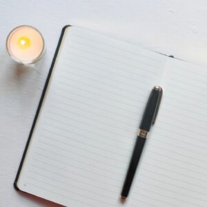 Mindfulness journaling with candle and notebook on minimal white desk
