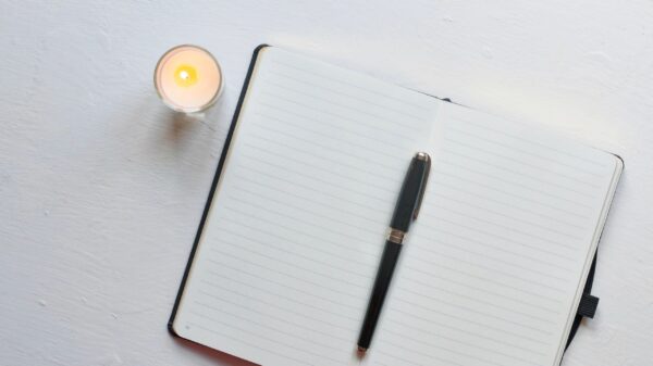 Mindfulness journaling with candle and notebook on minimal white desk